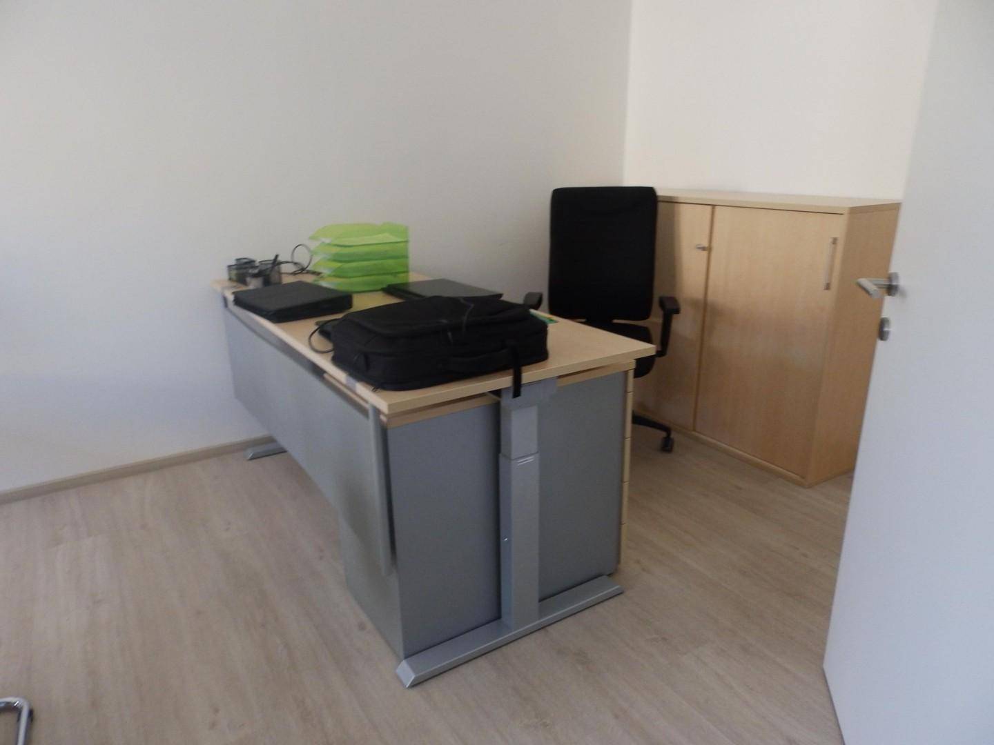 Büroecke mit modernem Schreibtisch, Bürostuhl und einem hellen Holzschrank.