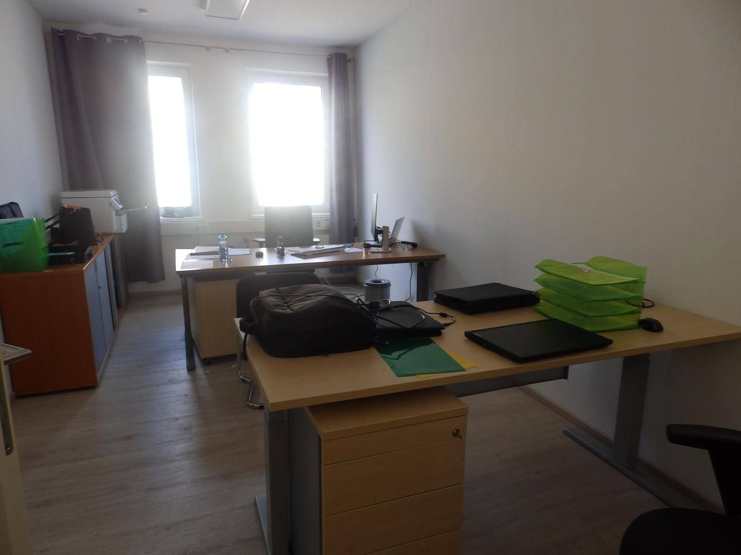 Geräumiges Büro mit zwei Arbeitsplätzen, Fenstern und praktischen Büromöbeln.