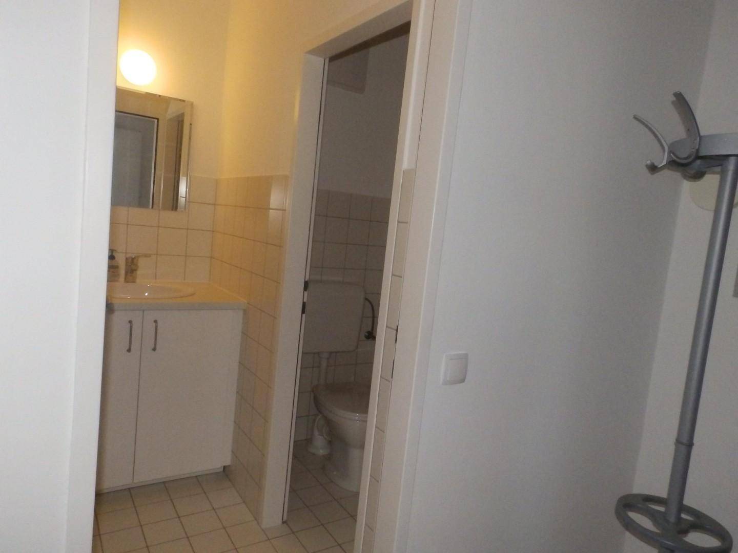 Badezimmer mit Waschbecken, Spiegelschrank und Blick in einen separaten Toilettenraum.