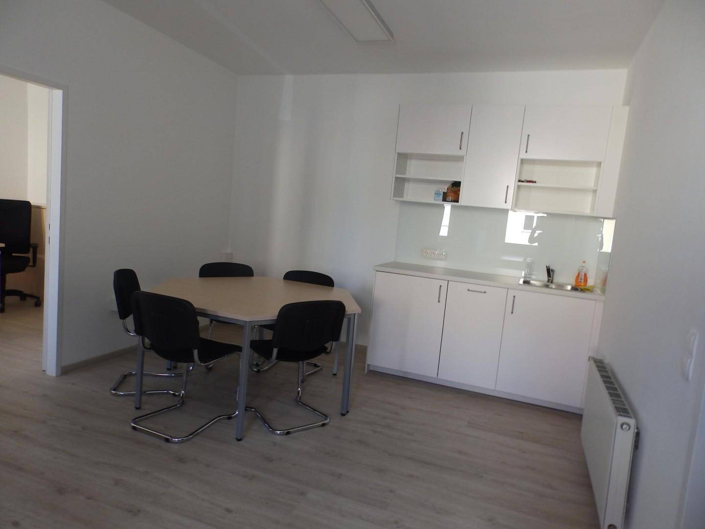 Heller Büroraum mit integrierter Teeküche, Besprechungstisch und Zugang zu weiteren Büros.