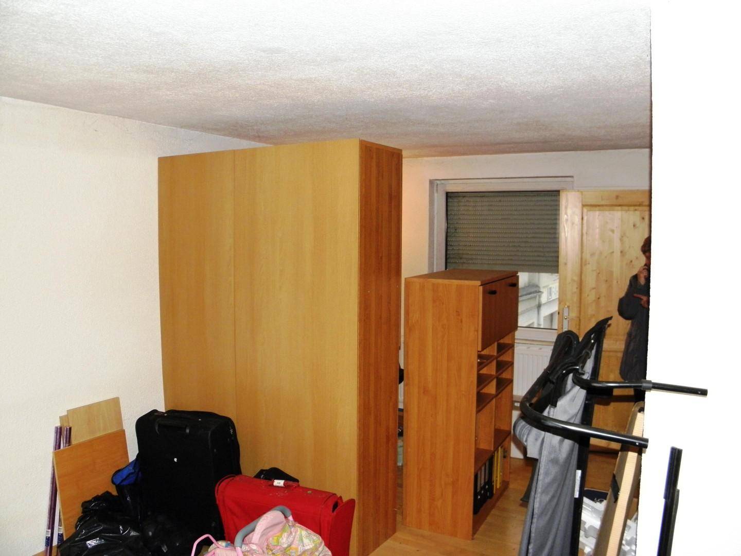 Zimmer mit hellen Holzschränken und einem Fenster mit Jalousien.