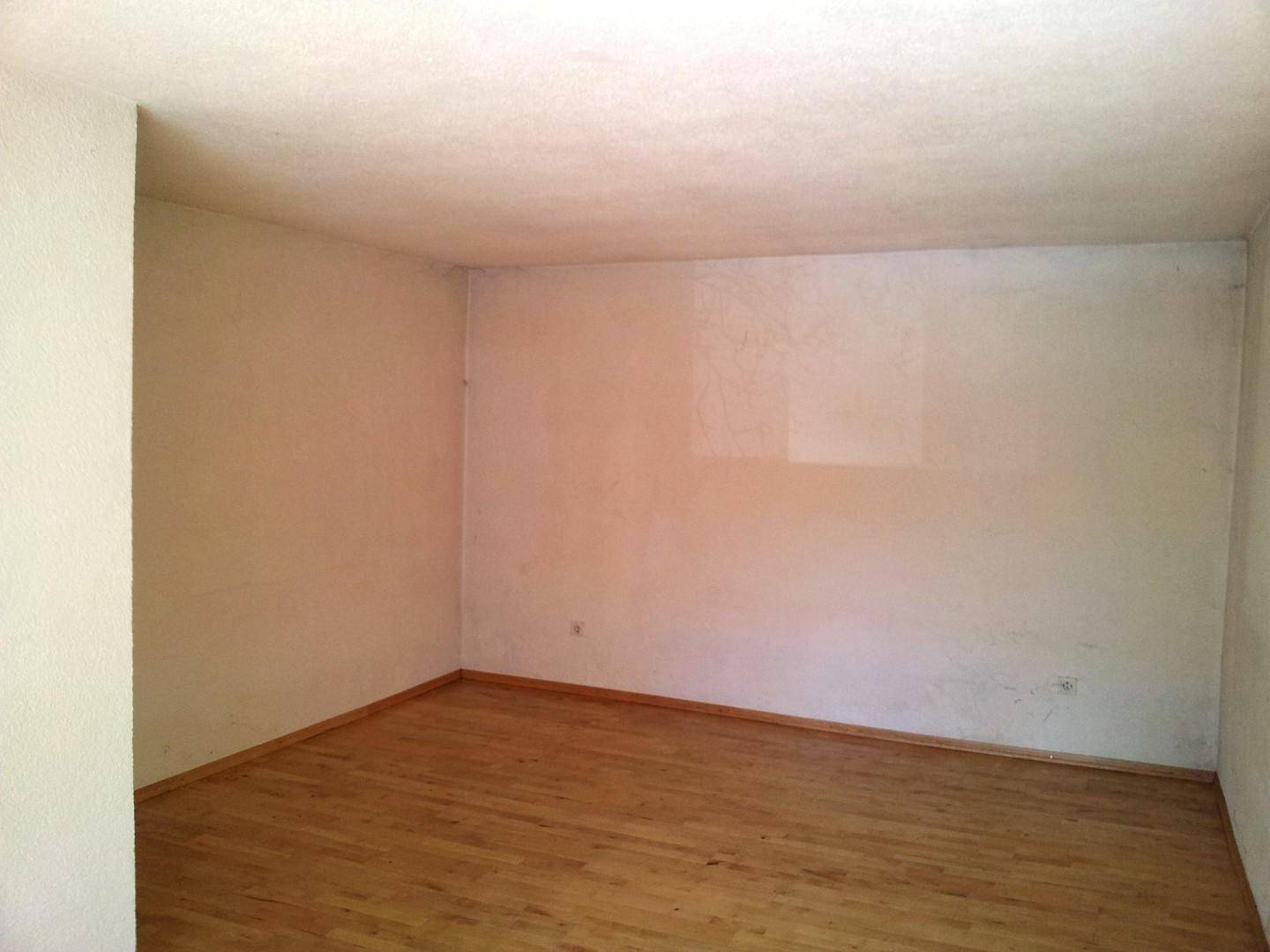 Heller, leerer Raum mit Holzfußboden und weißen Wänden, ideal für verschiedene Nutzungen.