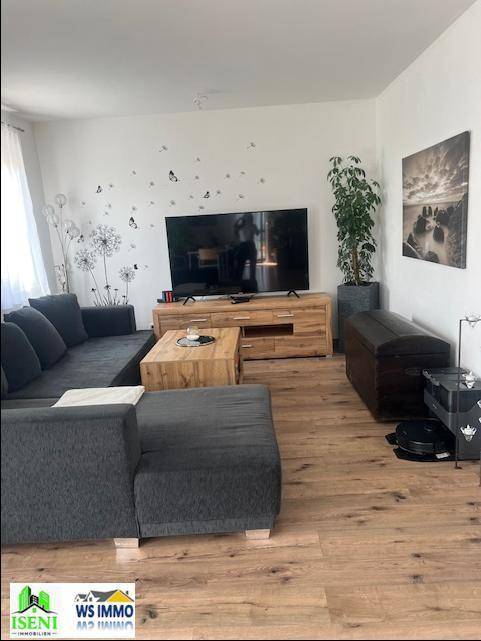 Geräumiges Wohnzimmer mit großem Sofa, Holztisch und Fernseher, dekoriert mit Wandstickern.