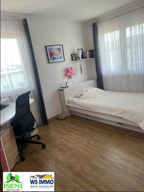 Helles Zimmer mit Einzelbett, Schreibtisch und Laminatboden, ideal als Kinder- oder Arbeitszimmer.