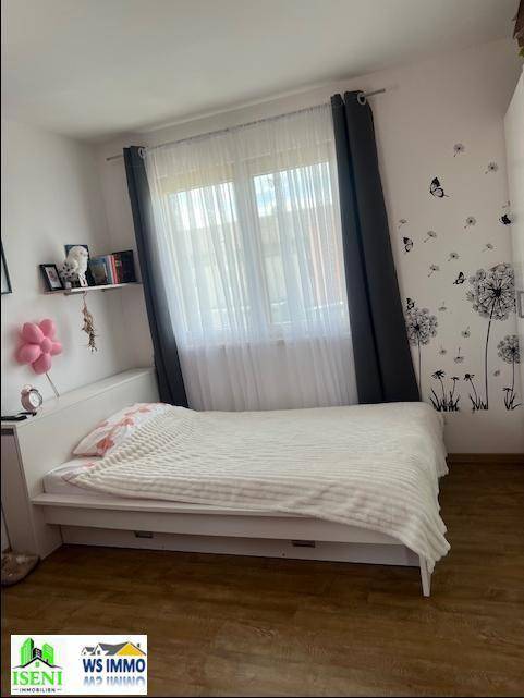 Helles Schlafzimmer mit Einzelbett, Laminatboden und dekorativen Wandstickern.