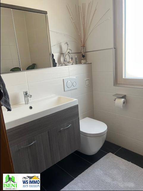 Modernes Gäste-WC mit wandhängendem WC, Waschbeckenunterschrank und Fliesen in Weiß und Schwarz.