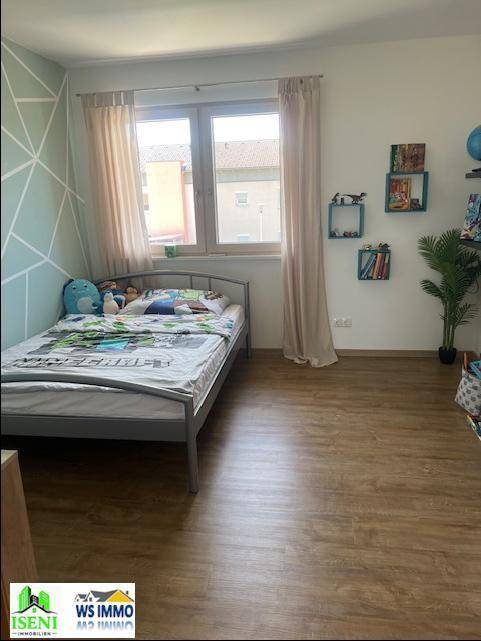 Kinderzimmer mit Einzelbett, Laminatboden und einer modern gestalteten Wand in Mintgrün.