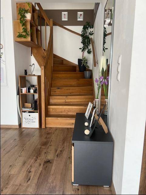 Eingangsbereich mit Holztreppe zum Obergeschoss, Laminatboden und dekorativen Pflanzen.