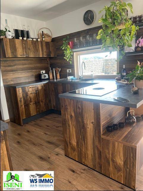 Geräumige Küche mit Holzschränken, Kochinsel und integriertem Induktionskochfeld.