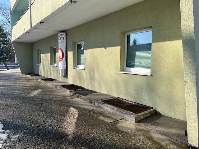 Nahaufnahme der Gebäudefassade mit Fenstern und einem Schild an der Wand.