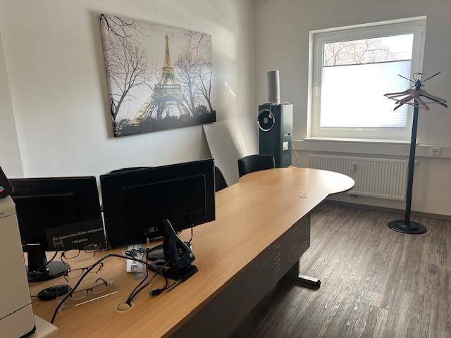 Büro mit großem Schreibtisch, Computern und einem Fenster mit Blick nach draußen.