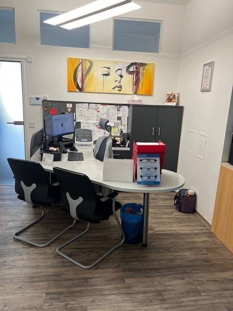 Modernes Büro mit ovalem Besprechungstisch, Kunst an der Wand und dunklen Schränken.
