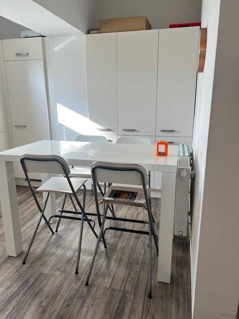 Moderne Küche mit weißen Schränken und einem Esstisch, ideal für Mahlzeiten und geselliges Beisammensein.