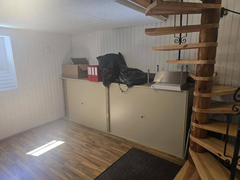 Lagerraum mit Holzwendeltreppe, Laminatboden und Regalen an der Wand.