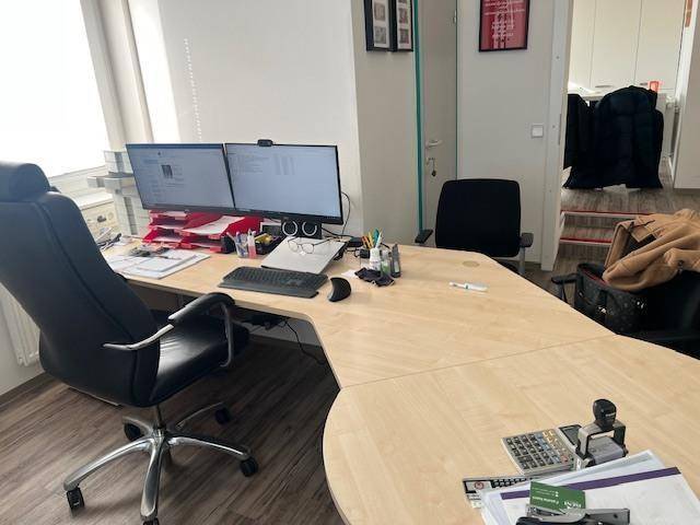 Großes Eckbüro mit zwei Monitoren, ergonomischem Stuhl und hellem Holzschreibtisch.