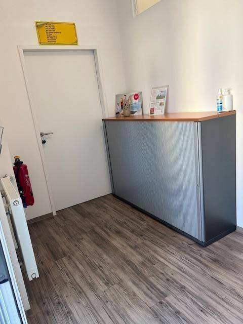 Büro mit einem Aktenschrank, weißer Tür und einem Heizkörper an der Wand.