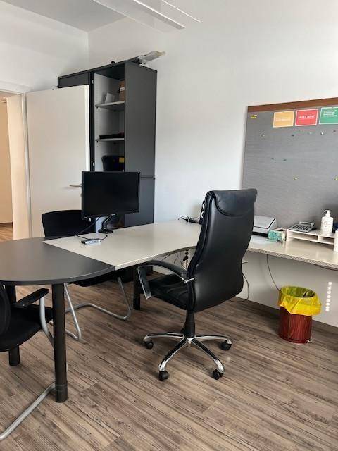 Modernes Büro mit dunklem Bürostuhl, Schreibtisch und Schränken, ausgestattet mit Laminatboden.