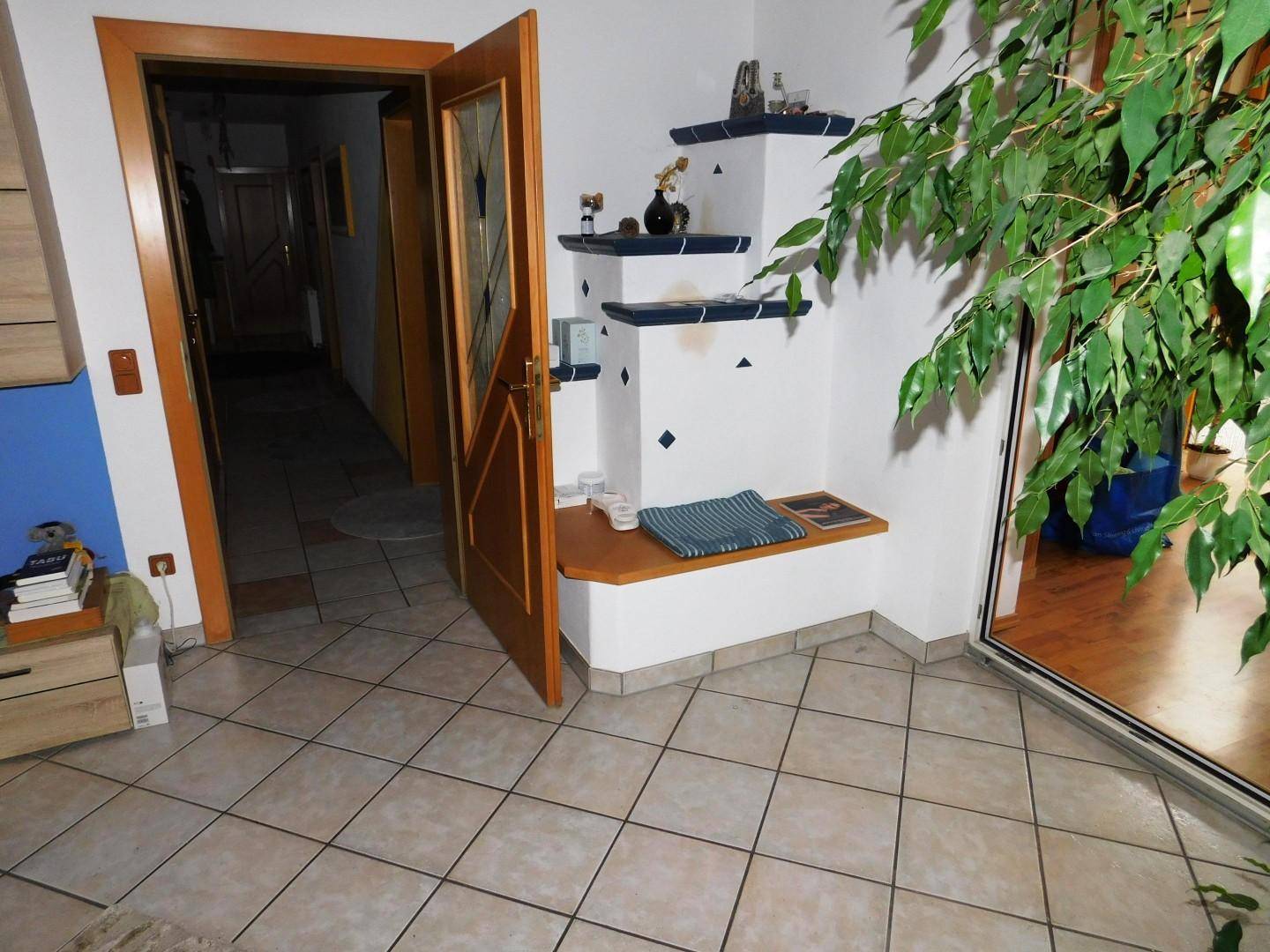 Heller Eingangsbereich mit Fliesenboden, Holztür und einer dekorativen Nische.
