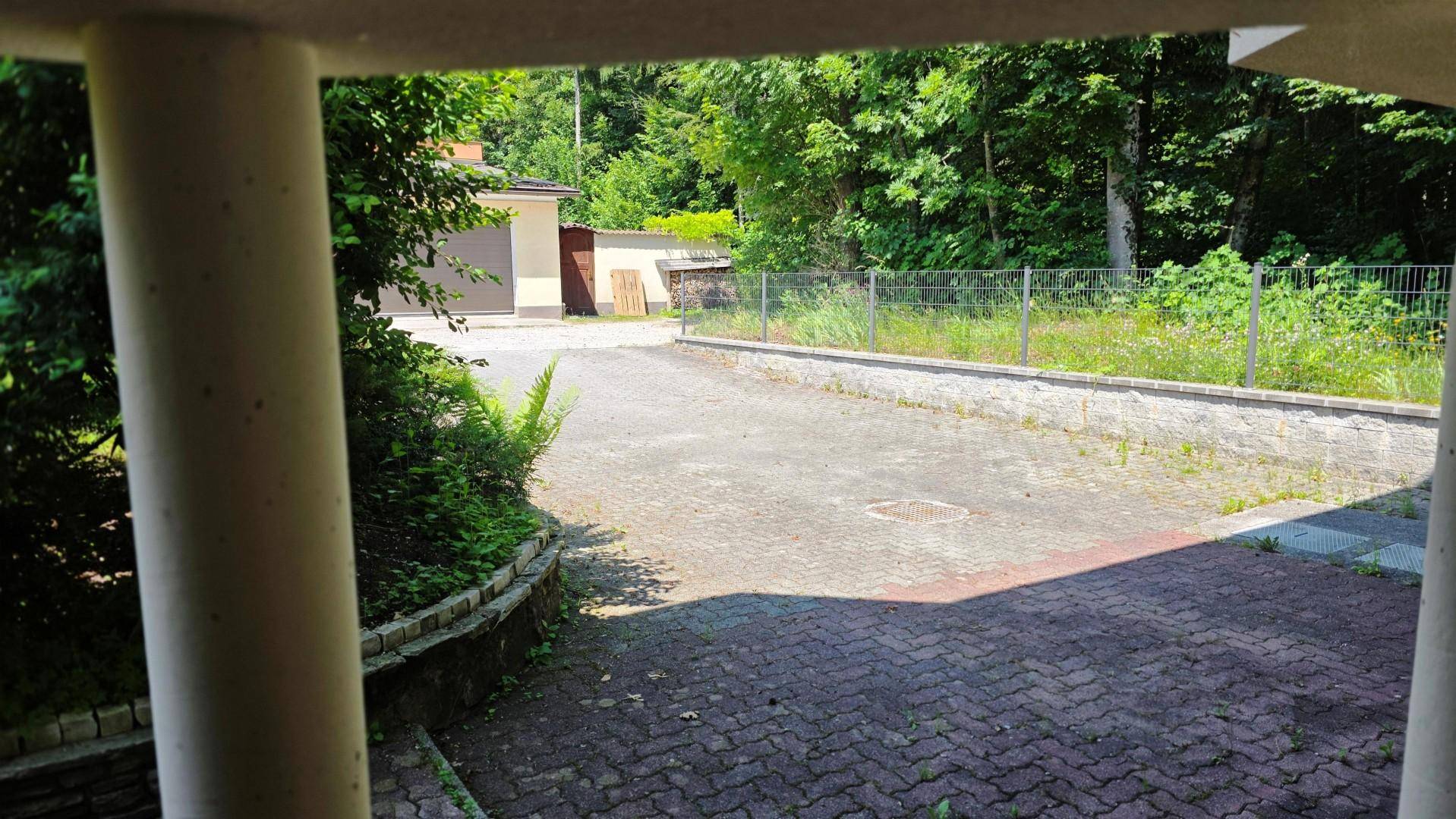 Blick von unterhalb des Hauses auf die gepflasterte Auffahrt und die Garage.