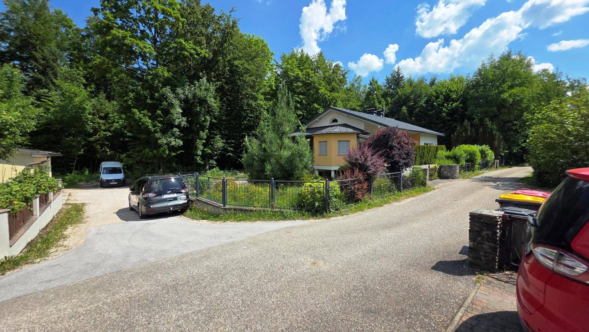 Das Haus ist von Bäumen umgeben und liegt an einer ruhigen Straße mit weiteren Wohnhäusern.