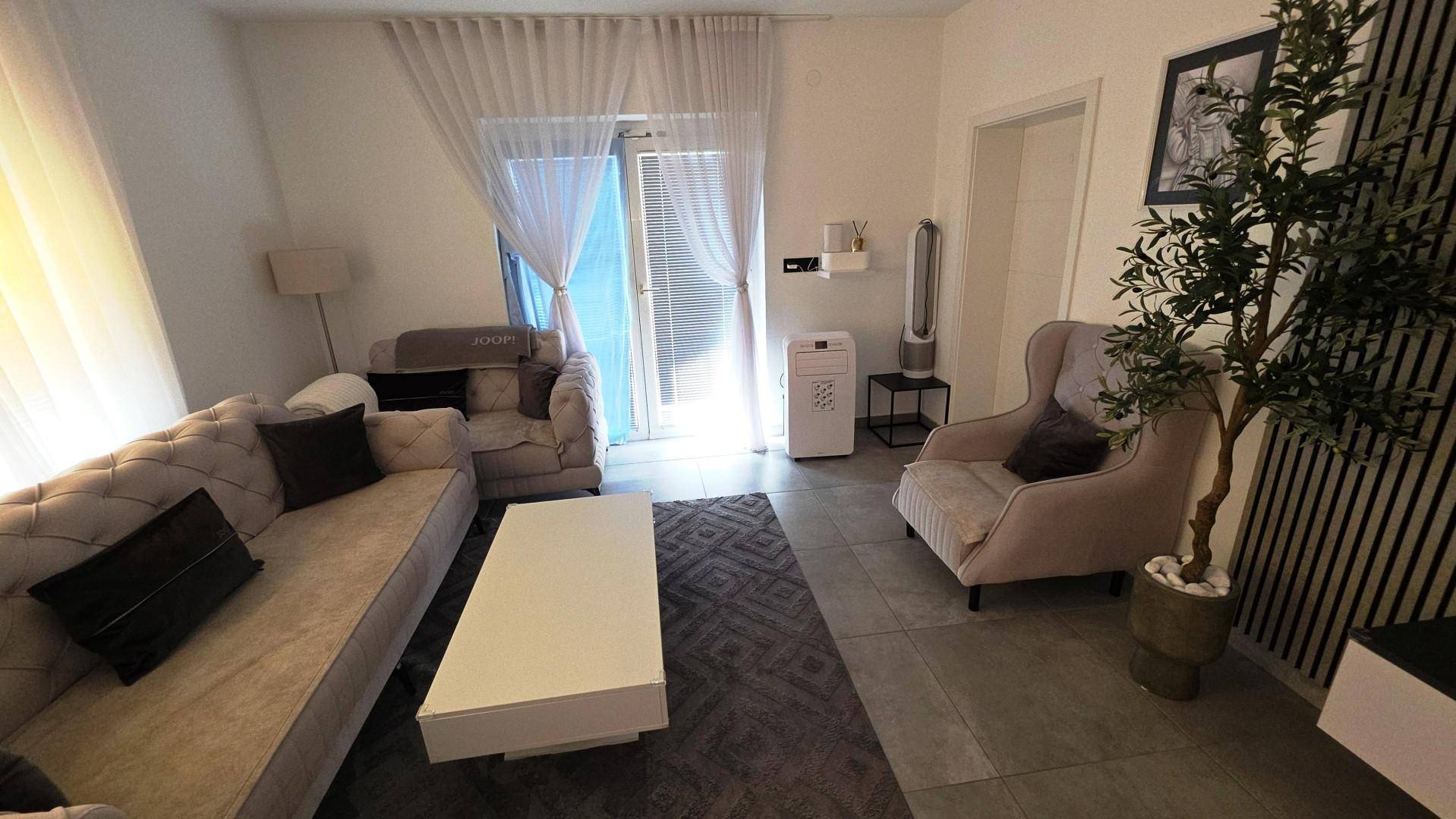 Helles Wohnzimmer mit bequemen Sitzgelegenheiten, großem Fenster und moderner Einrichtung.