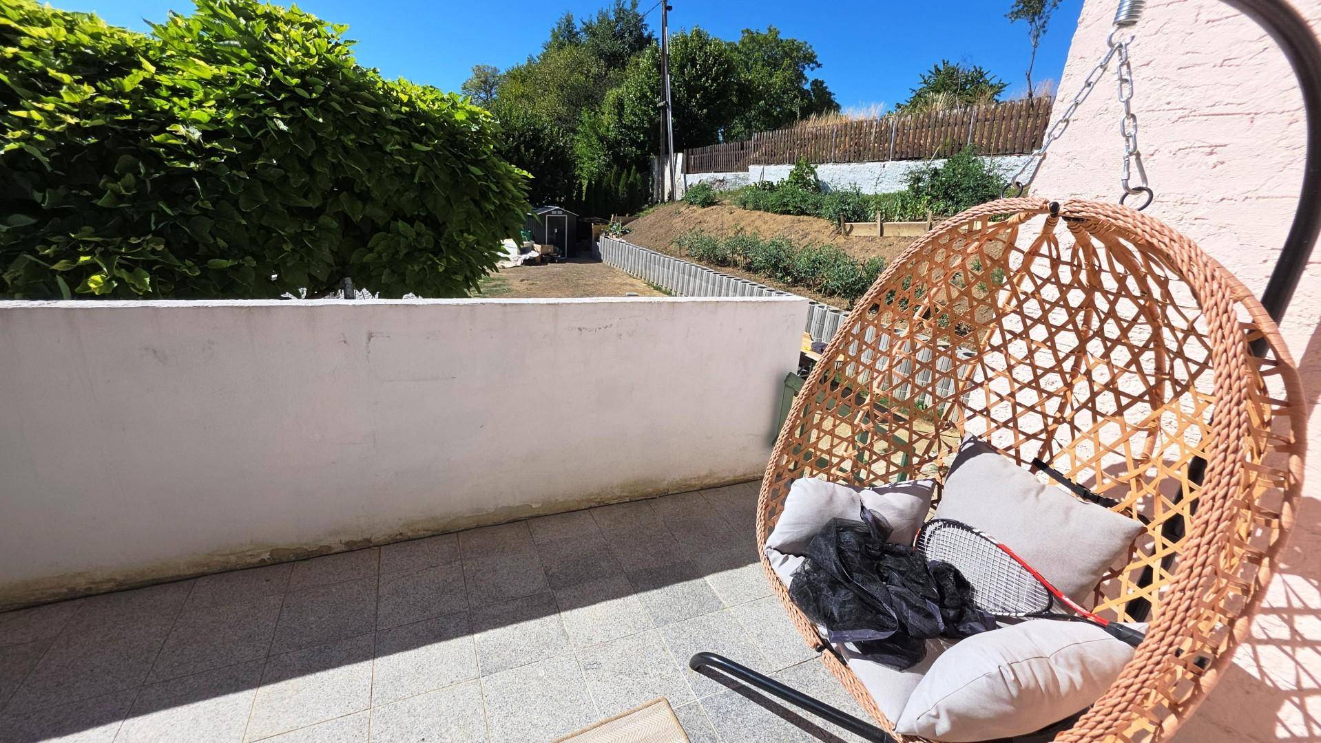 Terrasse mit Hängesessel und Blick auf den terrassierten Gartenbereich.