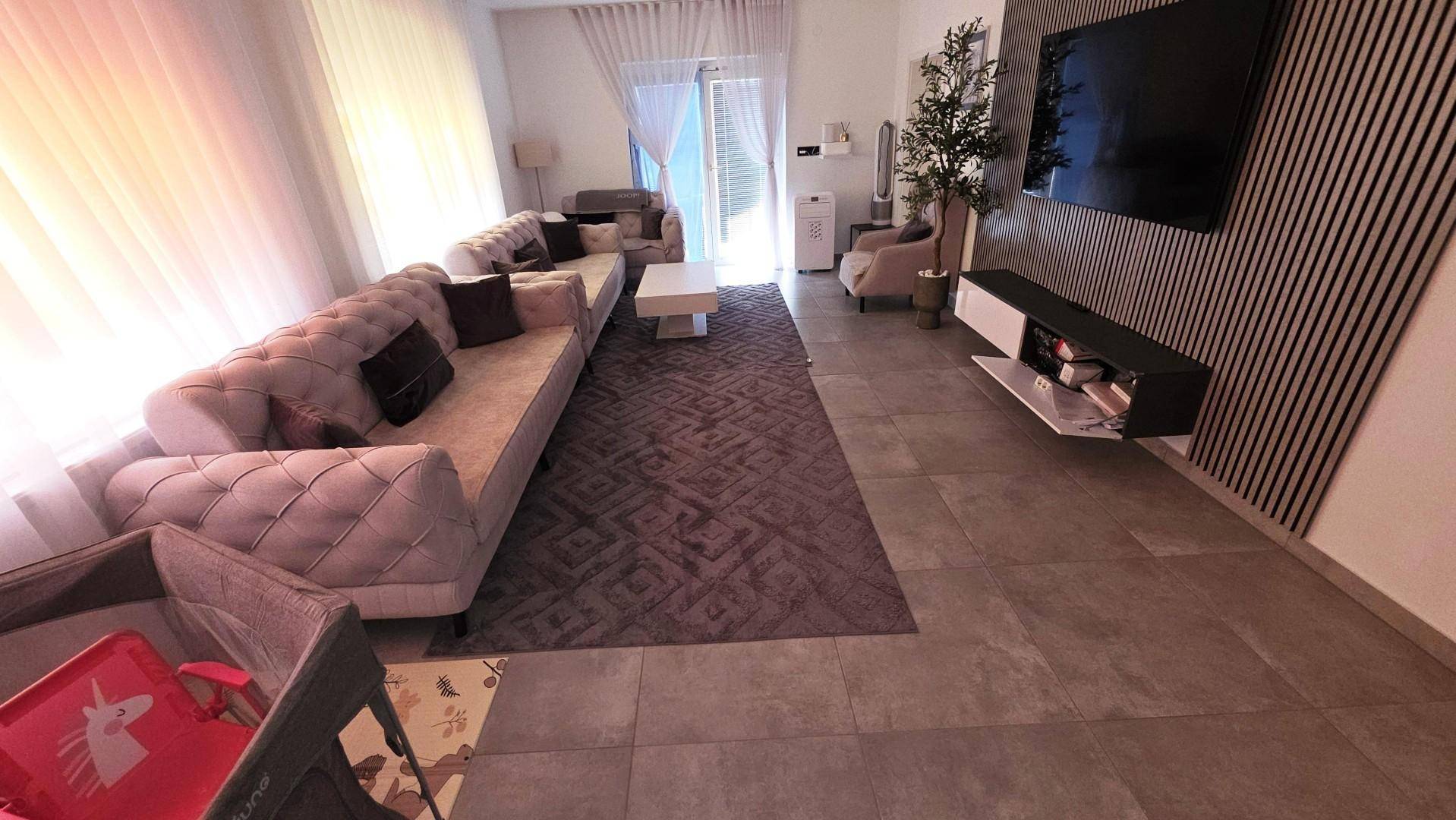 Gemütliches Wohnzimmer mit großem Sofa, Teppich und Blick auf den Eingangsbereich.