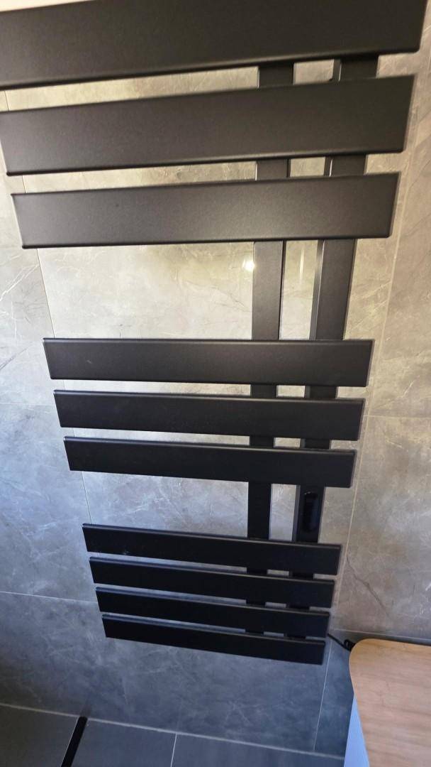 Moderner schwarzer Handtuchheizkörper an der Wand im Badezimmer.