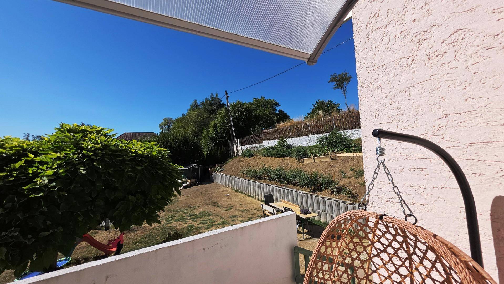 Außenbereich mit Hängesessel und Blick auf den Garten und die umliegende Natur.
