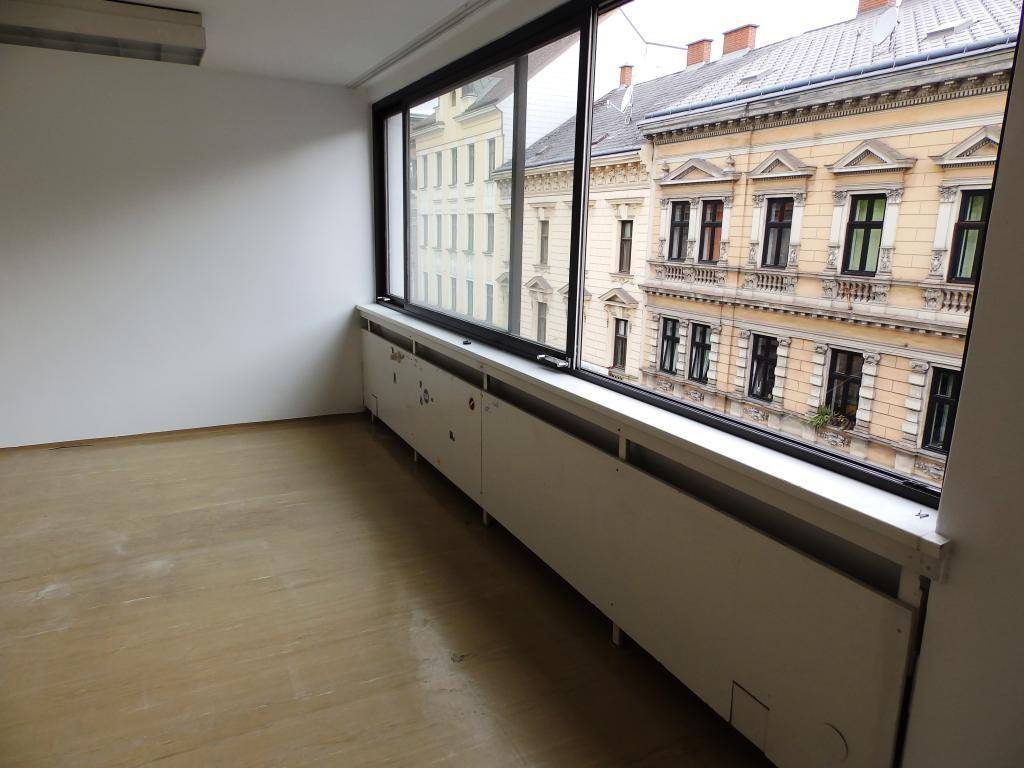 Heller Büroraum mit breitem Fenster und direktem Blick auf die historische Stadtbebauung.