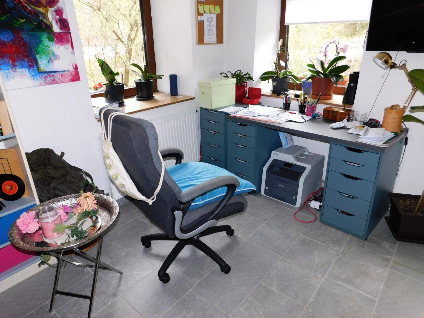 Helles Arbeitszimmer mit Schreibtisch, Bürostuhl und Blick ins Grüne durch die Fenster.