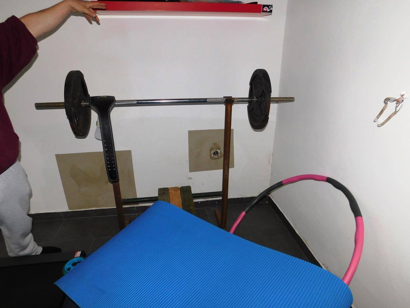 Raum eingerichtet als Fitnessbereich mit Hantelbank und Sportmatte für das persönliche Training.