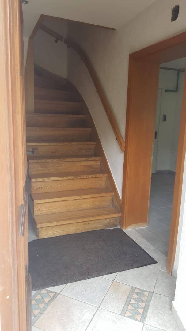 Eingangsbereich mit Holztreppe und gemustertem Fliesenboden, der in die oberen Etagen führt.