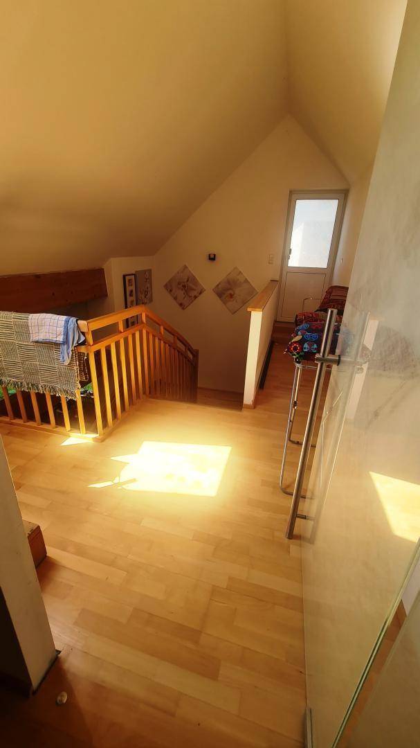Heller Flur im Dachgeschoss mit Holztreppe, Parkettboden und viel natürlichem Licht.