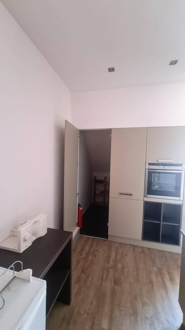 Moderne Küchenzeile mit Einbaugeräten und Zugang zu einem Abstellraum unter der Dachschräge.