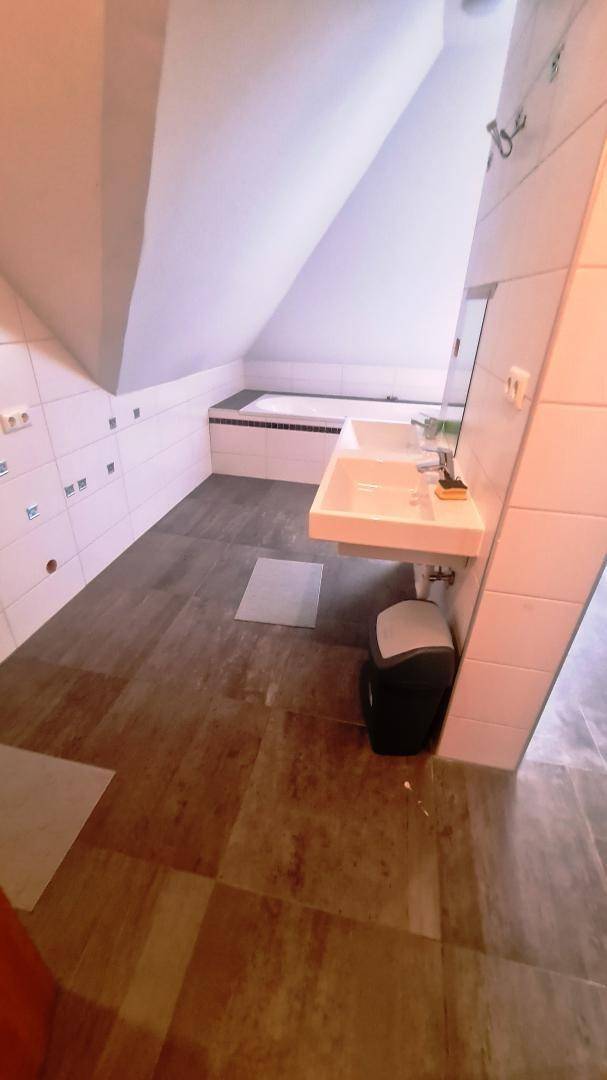 Geräumiges Badezimmer mit Doppelwaschbecken, Fliesenboden und Dachschräge für ein helles Ambiente.