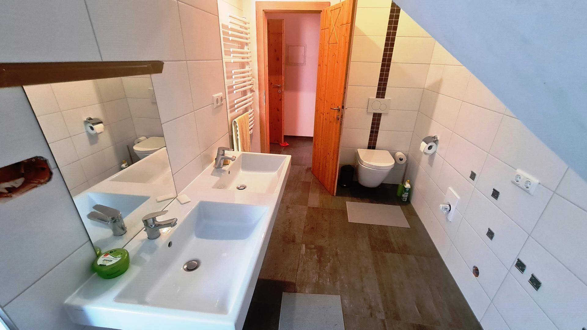 Modernes Badezimmer mit Doppelwaschbecken, Wand-WC und beheiztem Handtuchhalter.