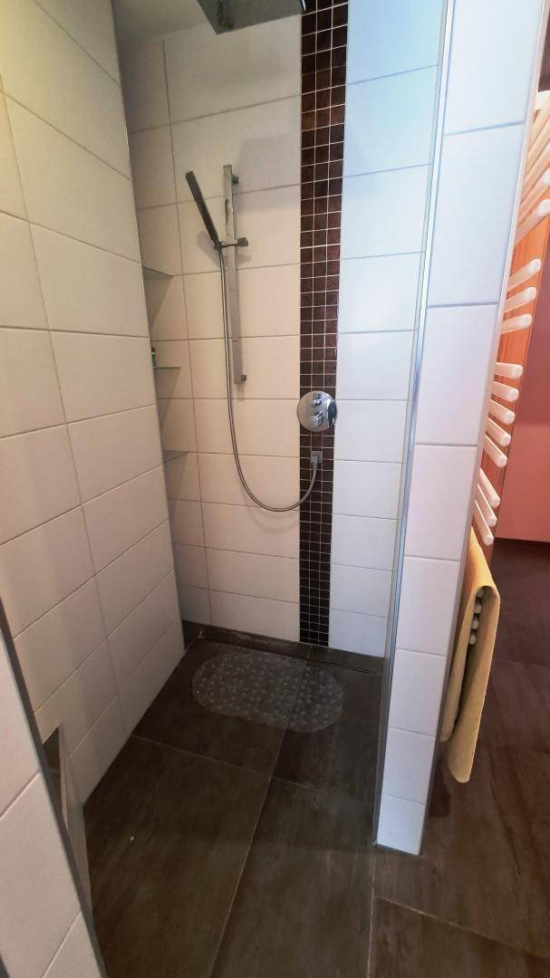 Gefliester Duschbereich mit Handbrause und moderner Gestaltung im Badezimmer.