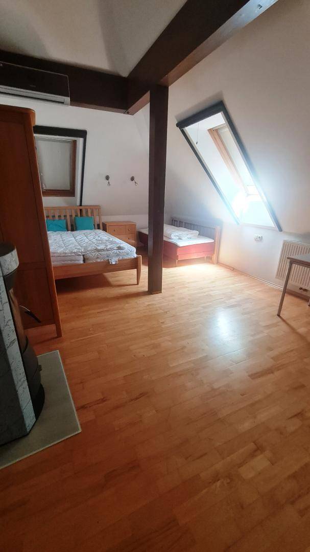 Helles Schlafzimmer im Dachgeschoss mit Holzboden, Klimaanlage und Dachfenster.