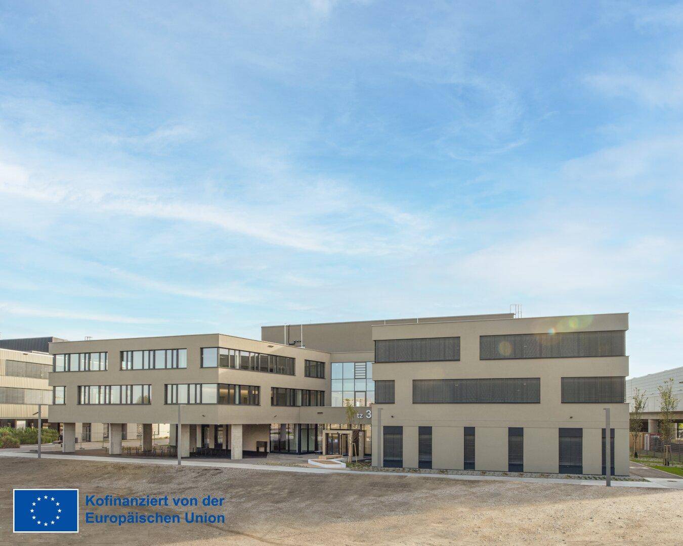 Weitläufiger Gebäudekomplex mit moderner Architektur, großen Fensterfronten und klarem Design unter blauem Himmel.