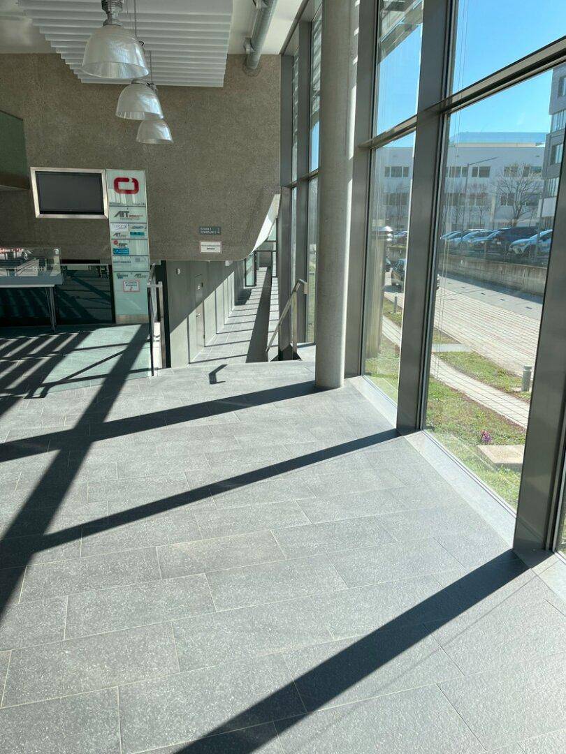 Heller, moderner Flur mit großen Fenstern, Fliesenboden und viel natürlichem Licht.