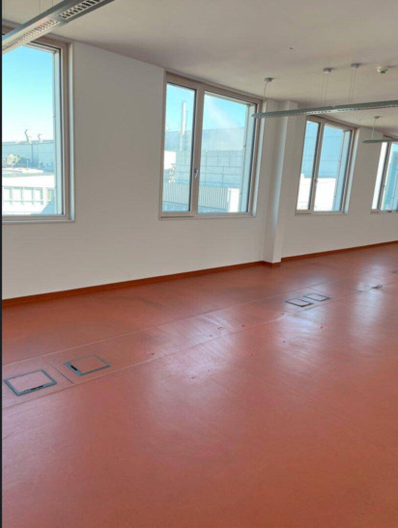 Großer Büroraum mit vielen Fenstern, die eine gute Belichtung und Ausblick bieten.