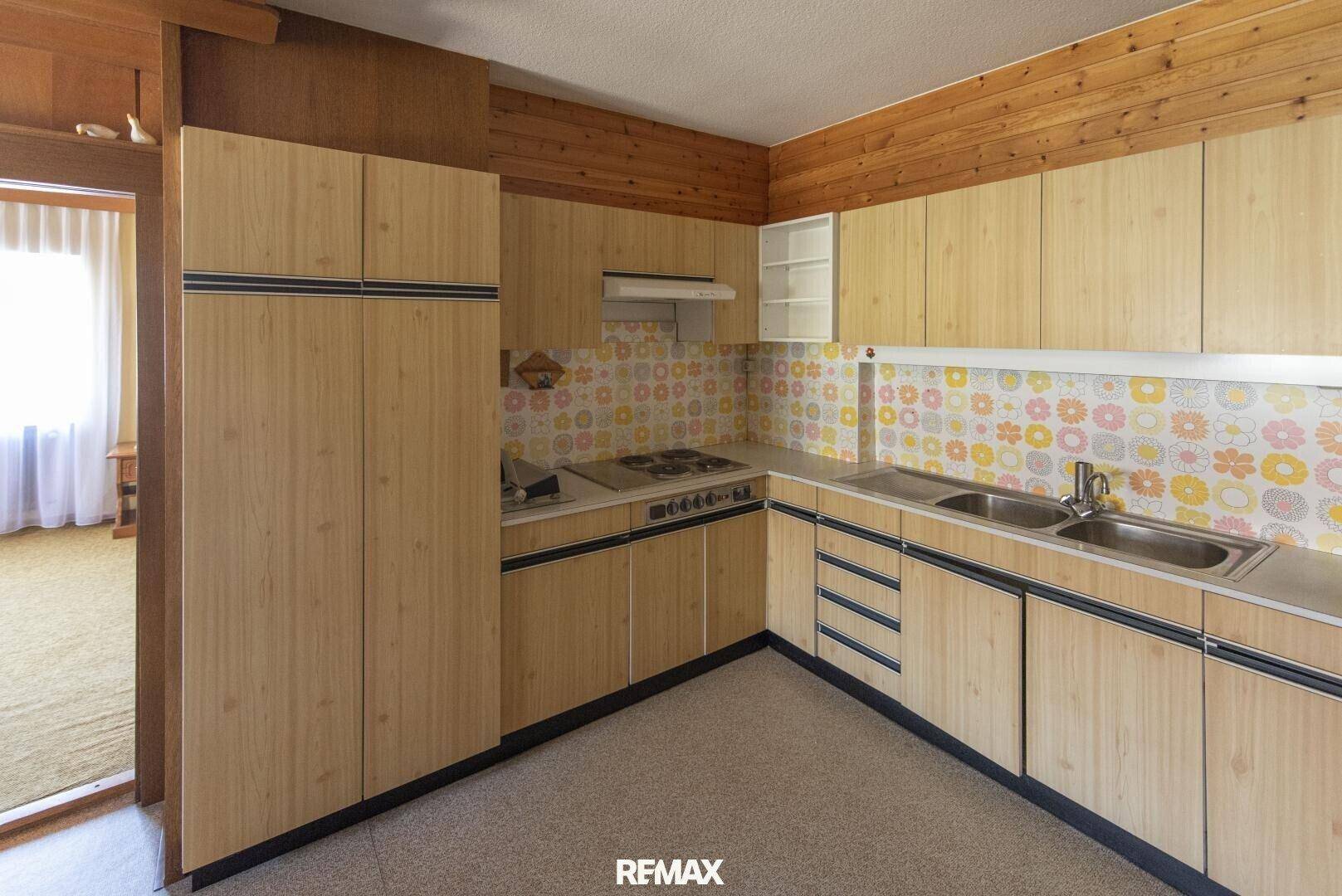 Funktionale Küche mit Holzfronten, Spüle und Retro-Wandfliesen.