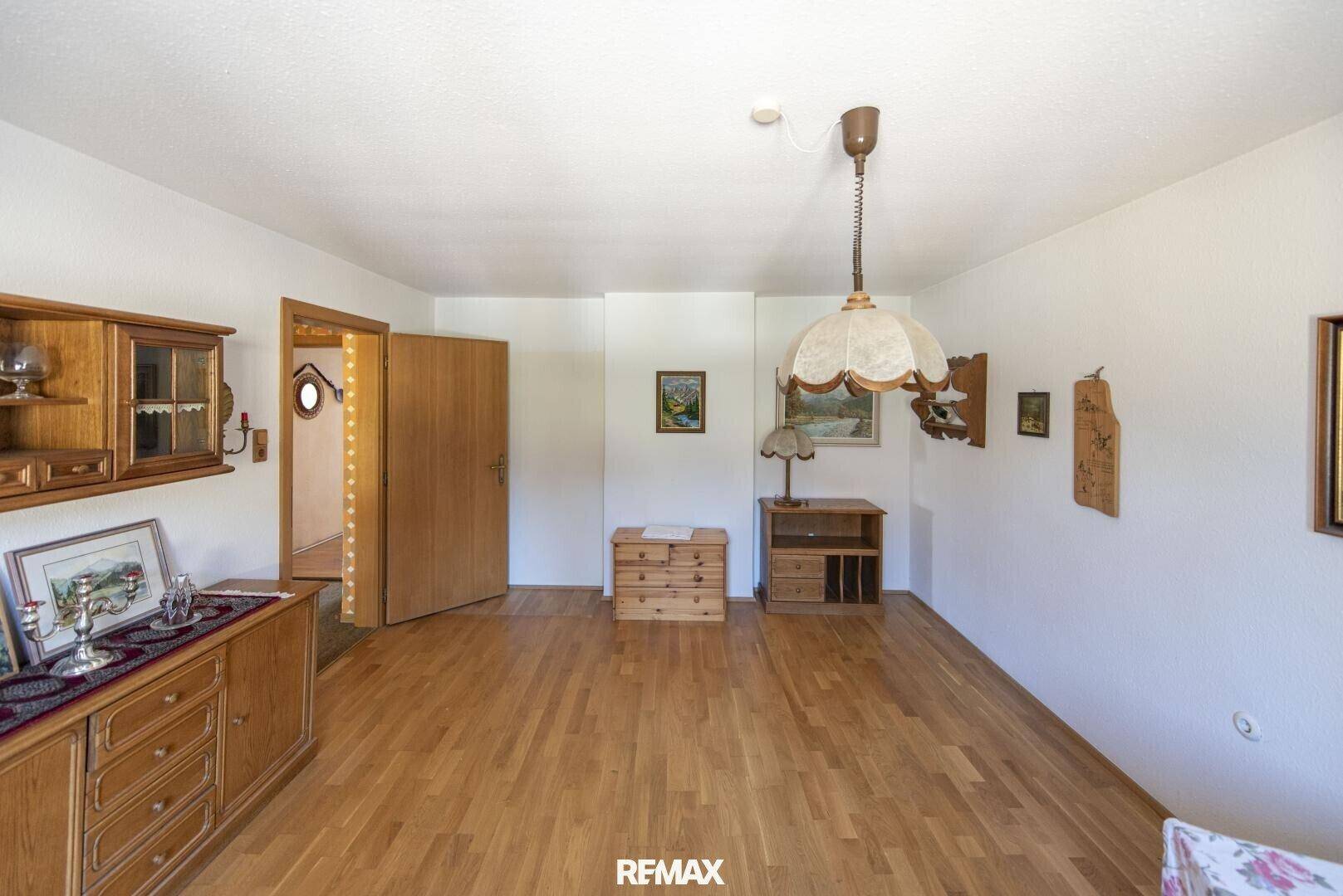Geräumiges Wohnzimmer mit Holzboden und traditionellen Holzmöbeln.