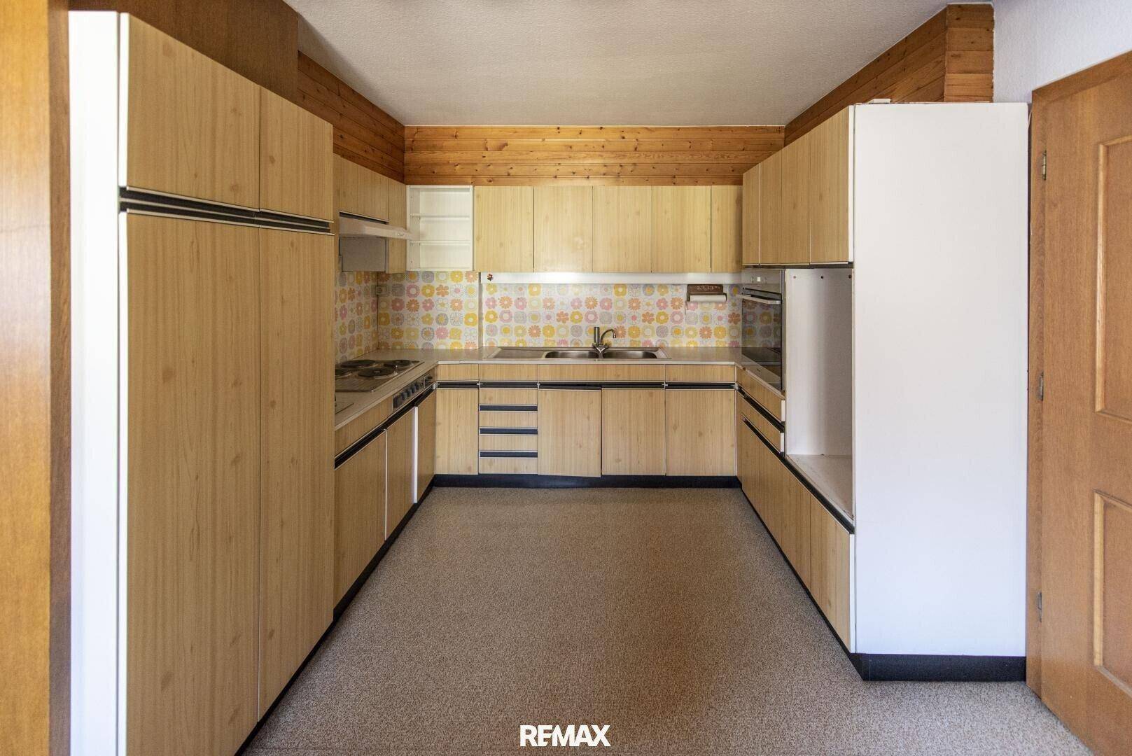 Küche im Retro-Stil mit Holzschränken, gemusterten Fliesen und Linoleumboden.