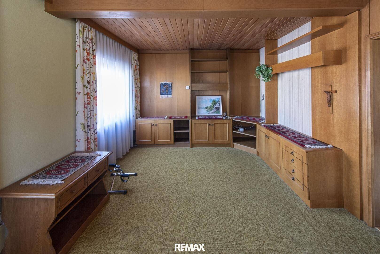 Geräumiges Wohnzimmer mit Holzvertäfelung, Teppichboden und Einbauschränken im traditionellen Stil.