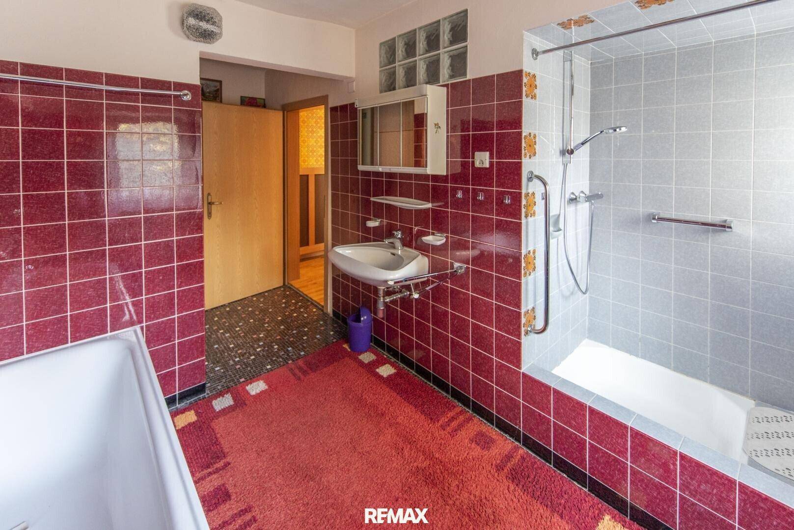 Badezimmer im 80er-Jahre-Stil mit roten Fliesen, Badewanne und Dusche.