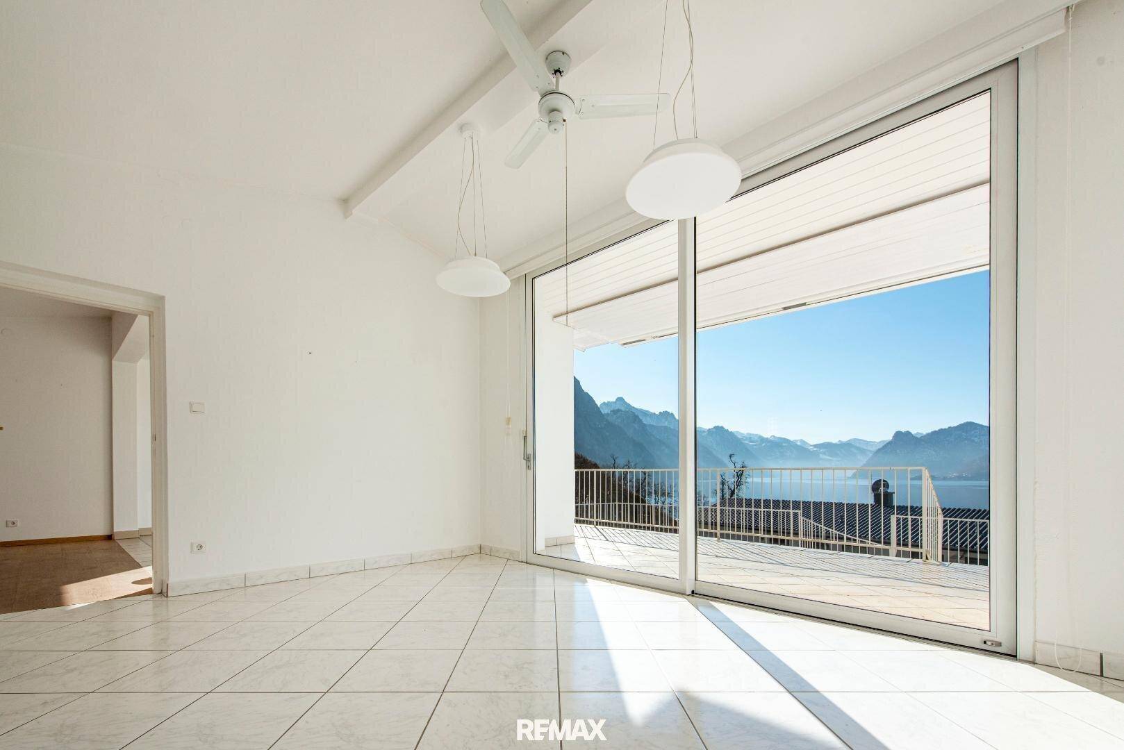 Helles Wohnzimmer mit großen Schiebetüren, die einen atemberaubenden Blick auf See und Berge bieten.