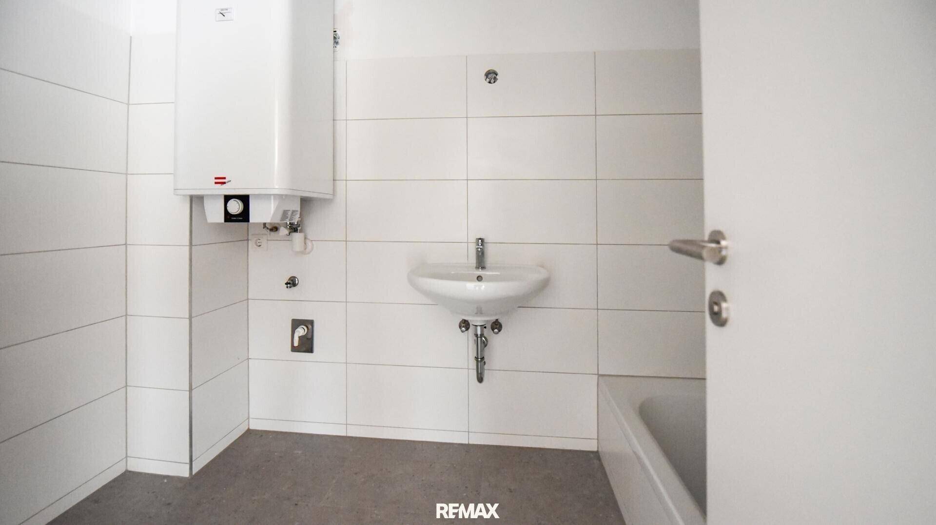Helles Badezimmer mit weißen Fliesen, Waschbecken und Badewanne, bereit zum Einbau.