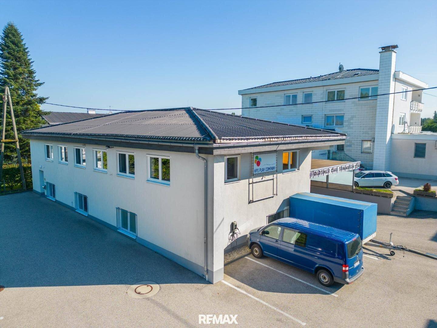 Luftaufnahme eines Gewerbegebäudes mit einem blauen Lieferwagen und Solaranlage auf dem Dach.